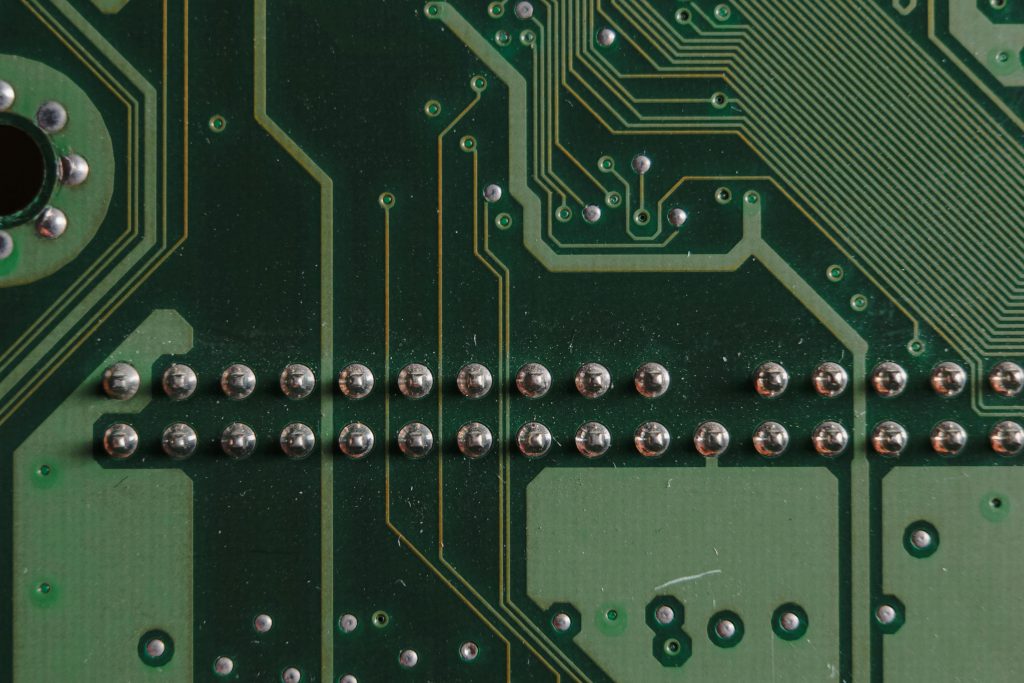 Close-up of a green PCB showing soldered pins and copper traces