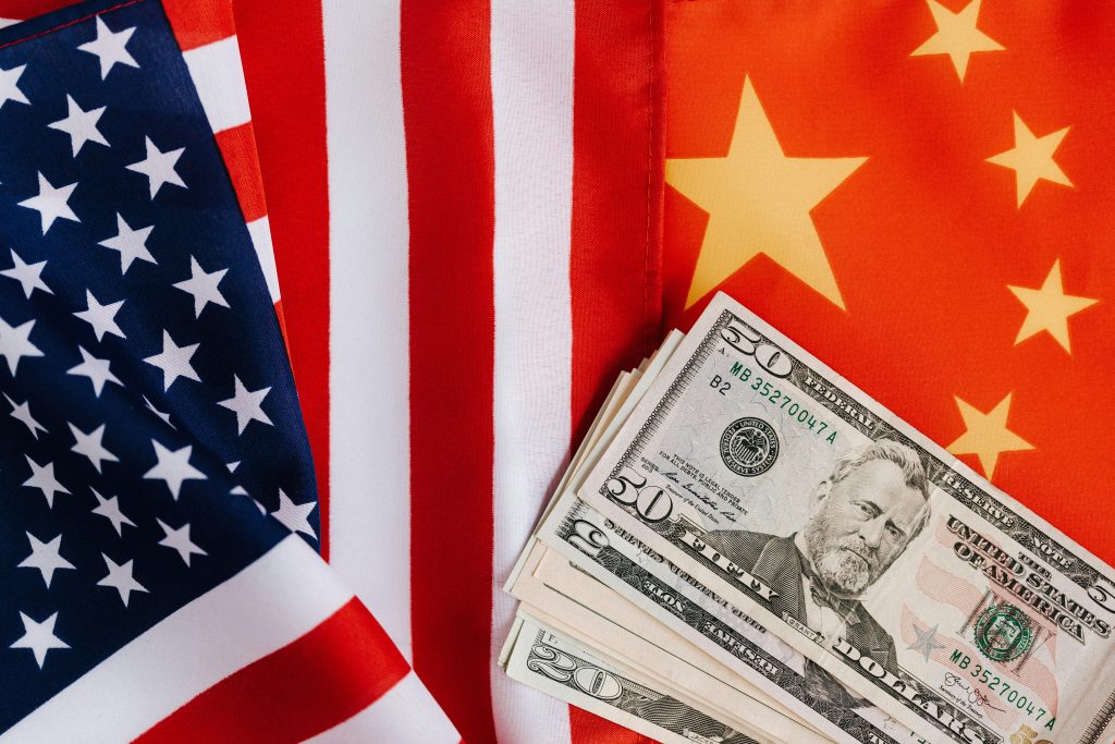 U.S. and China flags with stack of dollar bills symbolizing tariff impact on international trade and business costs